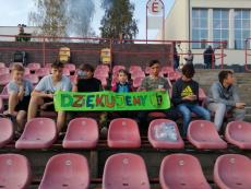 Pusty stadion piłkarskich - siedzenie w dwóch ostatnich rzędach siedzi grupa dzieci z kolorowym napisem dziękujemy na zielonej kartce.jpg