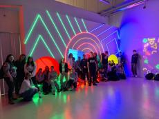 Wychowankowie pod kolorową podświetloną ścianą w FUNzeum