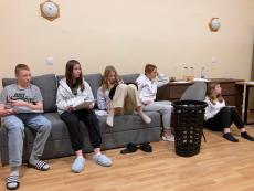 Wychowankowie siedzący  na szarej kanapie i słuchających wykładu 