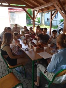Wychowankowie wraz z pracownikami Domu Dziecka w trakcie zakończenia roku szkolnego spożywający posiłek