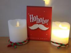 Zapalona świeczka oraz czerwona kartka świateczna