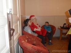 Zdjęcie to ujęcie z boku - widać Świętego Mikołaja siedzącego na fotelu - po jego lewej stronie siedzi chłopiec a po prawej dziewczynka.JPG