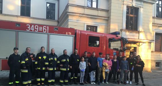 Grupowe zdjęcie dzieci i strażaków na tle wozu strażackiego i budynku Domu Dziecka w Cieszynie.JPG